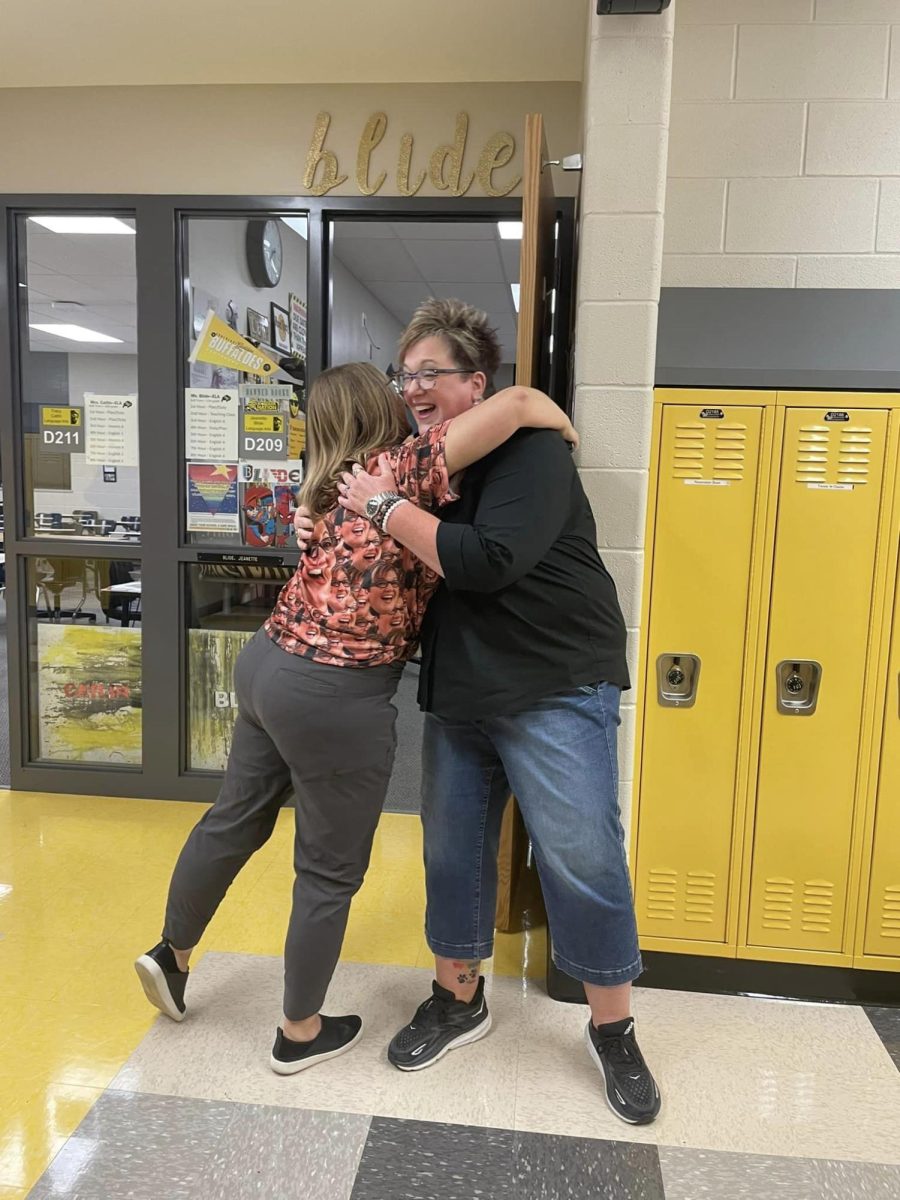 English teacher Tracy Catlin embraces English teacher Jeanette Blide while wearing a shirt covered in her face.